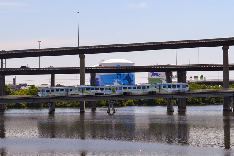 A low-emission commuter train traveling over a bridge on the bay.