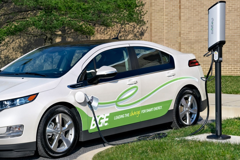 Electric vehicle charging beside a sidewalk.
