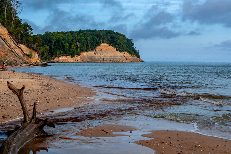 Cliffs rise in the distance above a sandy beach.
